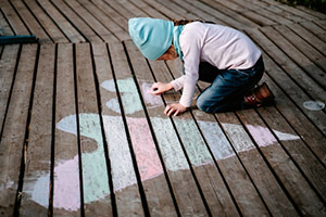 child drawing a heart on the ground with chalk