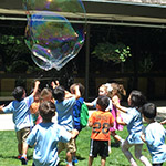 children chasing a giant bubble outside