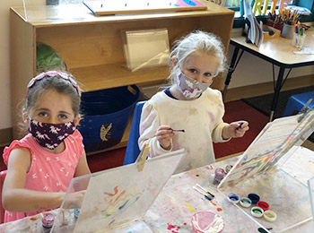 two girls paint wearing masks
