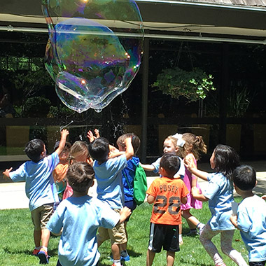 children outdoors chasing a giant bubble