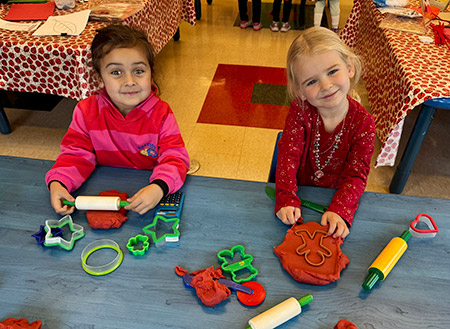 two girls sitting at a table playing with play dough